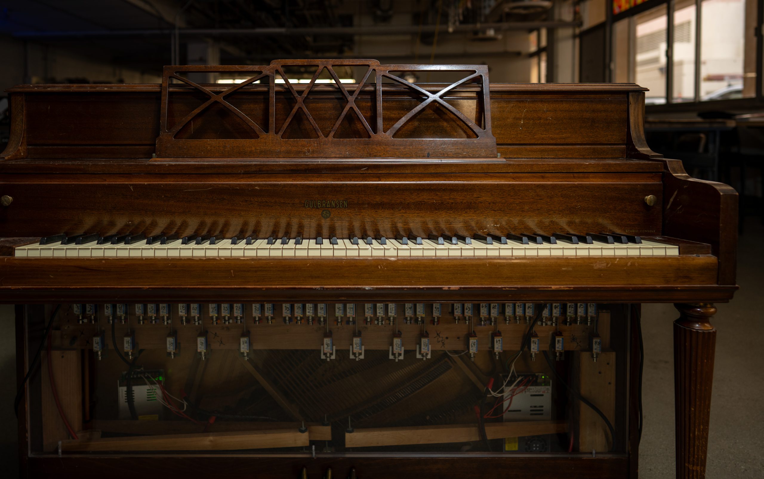 The piano with electrical components underneath.